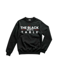 A black crewneck sweatshirt with a bold graphic print reading 'THE BLACK MAN'S TABLE' in white letters with red accent lines, displayed flat against a solid white background.